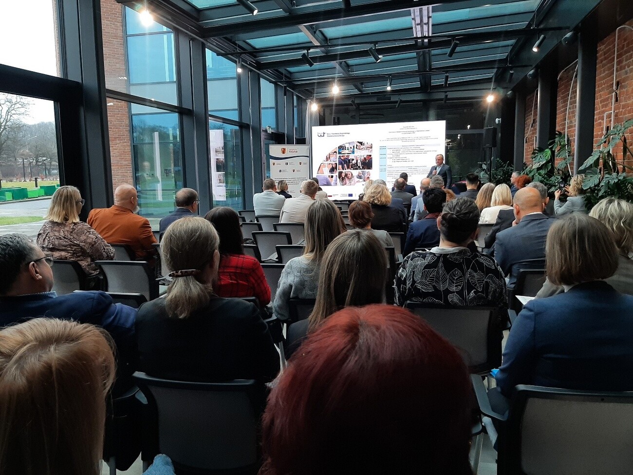 Na zdjęciu widać uczestników konferencji, z przodu zaś jest ekran na którym widać spot reklamujący Strategiię Kształcenia Zawodowego Województwa Łódzkiego